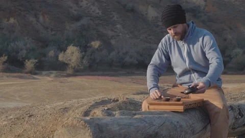 Outdoors man with a beard pours tea from a clay teapot from yixing into bowls Stock Footage 119336513