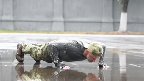 Outdoors training. man doing push up on wet place in military clothing Stock Footage 131396809