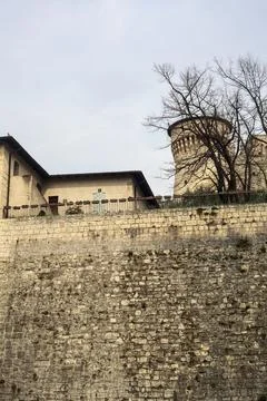 Outer boundary wall of a castle with trees and a cloudy sky as background Stock Photos