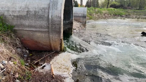 Outfall pipe, discharging water or treated effluent into river. Wastewater Stock-Footage 324664778