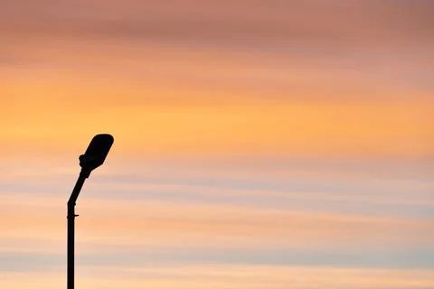 The outline of a lone lantern against the sky. Beautiful sunset, clouds in th Foto stock