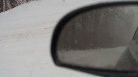 Outside the car window, snow falls beautifully. The dog "spy" runs alongside us. Stock Footage 100010472