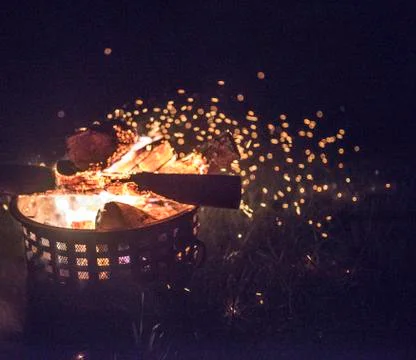 Outside fire inside of a fireproof canister with embers in the air Stock-Fotos