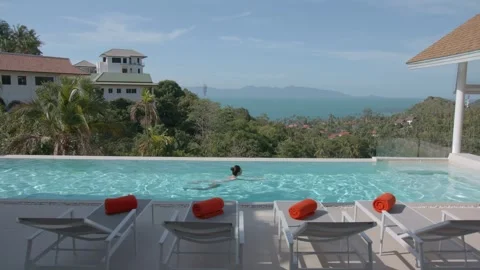 Outside pool with lounge area in spa resort, woman swimming in it, amazing view Stock-Footage 248433104