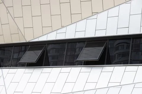 Outside view on white tiled wall of building with few black tinted windows Stock Photos
