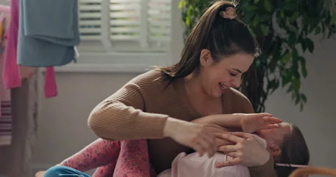 Outside the window is sunny day. Happy mother holds six-year-old daughter in Stock Footage 218315645