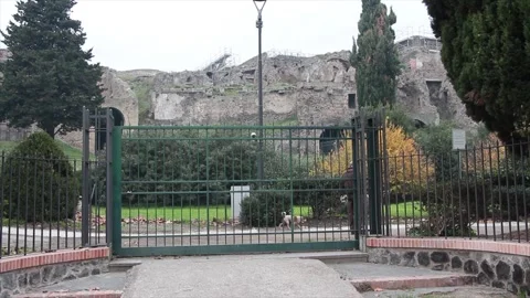 Outskirts of pompei shot through black metal gate with elderly man walking Stock Footage 252148449