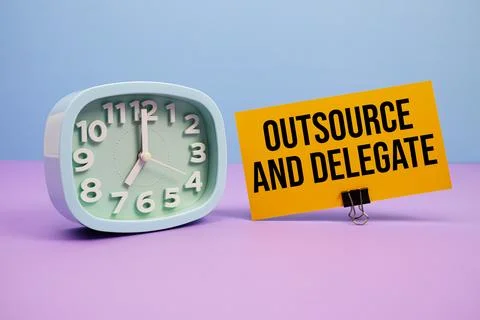 Outsource And Delegate text and alarm clock on blue and purple background Stock Photos