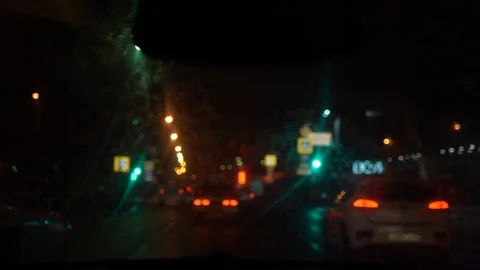 Outward view through a dirty wet windshield from inside the car in defocus.  Stock Footage 107998752