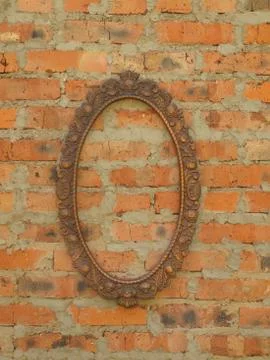 Oval bronze frame on the background of an old brick wall. Stock Photos