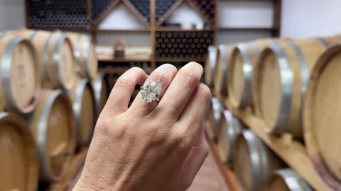 Oval diamond engagement ring in elegant wine cellar with soft warm light Stock Footage 319691948