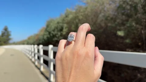 Oval diamond engagement ring moving along white fence walkway in Los Angeles Stock Footage 320313909