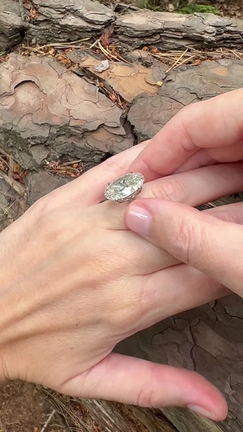 Oval diamond ring held by hands against textured tree bark, vertical video. Video stock 315342677
