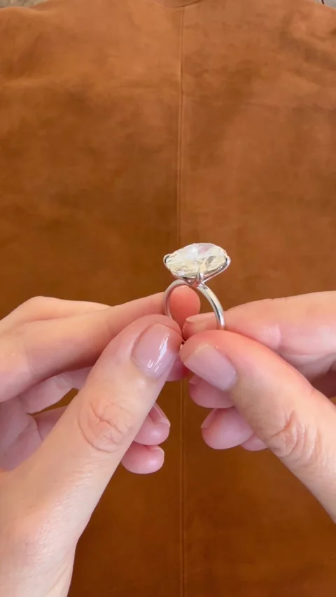 An oval diamond solitaire engagement ring held by fingers in vertical video Stock Footage 317019143