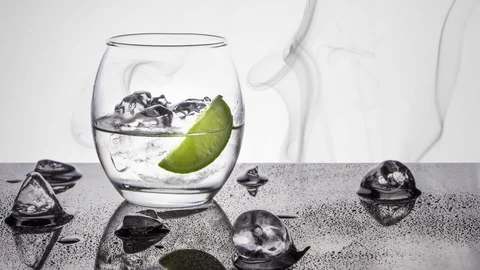 An oval glass of clear vodka rum or gin spirit with a wedge of lime and a ice Vídeo Stock 106361940