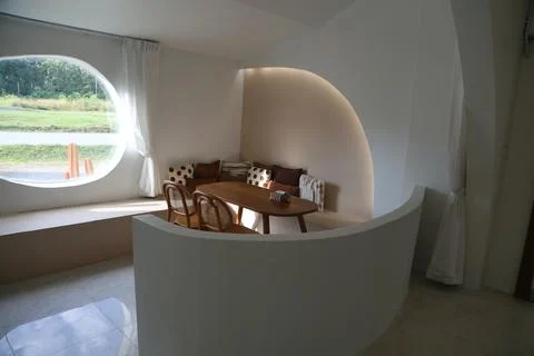 An oval-shaped room with a rounded window, curved white walls, and a table .. Stock Photos