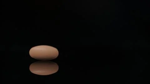 Oval-shaped tablet isolated on a black background with reflections. Concept of Stock Photos
