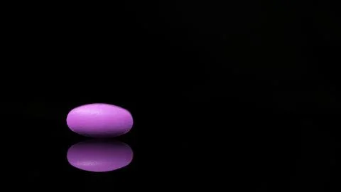 Oval-shaped tablet isolated on a black background with reflections. concept of Stock Photos