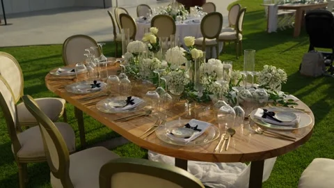 Oval Wooden Wedding Table Set With White Flowers And Gold Cutlery On A Lawn Stock-Footage 340595614