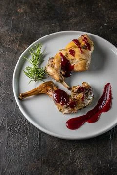 Oven Baked rabbit legs with cranberry sauce and rosemary. Rabbit confit Stock Photos
