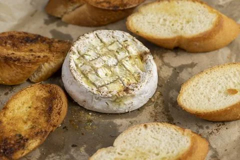 Oven-fried round soft white cheese in a mold with pieces of fried crispy bagu Stock Photos