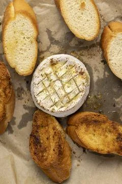 Oven-fried round soft white cheese in a mold with pieces of fried crispy bagu Stock Photos