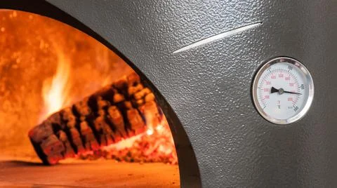 Oven with thermostat.  Burning wood in background Stock Photos