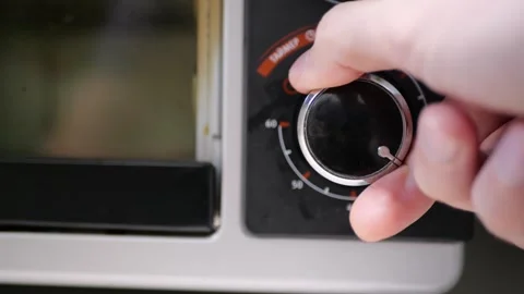 Oven timer being set cooking duration rotating dial close up hand operation Stock Footage 320897861