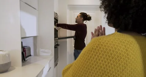 Oven timer ringing as diverse couple pulling pie tray with towel in home Stock Footage 317768413