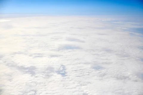 Over clouds top view from aircraft window, thick white blue clouds looks like Stock Photos