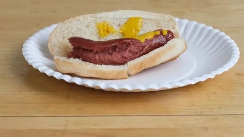Over cooked, disgusting looking hotdog on a paper plate. Stock Footage 138186771