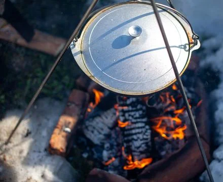 Over the fire hangs a pot in which to cook food. Stock Photos