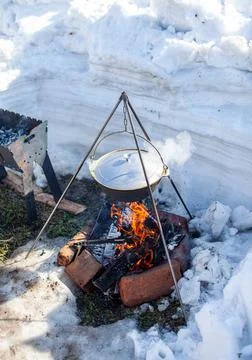 Over the fire hangs a pot in which to cook food. Stock Photos