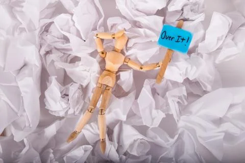Over it sign held by jointed doll laying on crumbled up paper Stock Photos