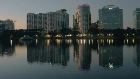 Over Lake Eola flying towards buildings at Dusk water fountain below Orlando Stock Footage 118235402