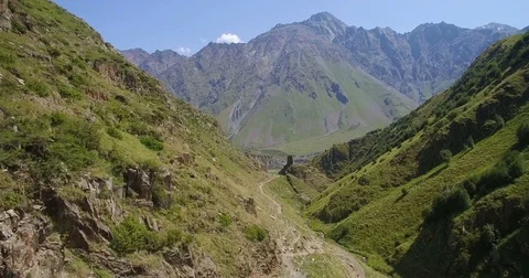 Over path in  green gorge towards  high mountain aerial view Vidéo 83082194