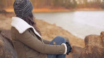 Over right shoulder close up of beautiful woman on rock at a lake. Stock Footage 85801007