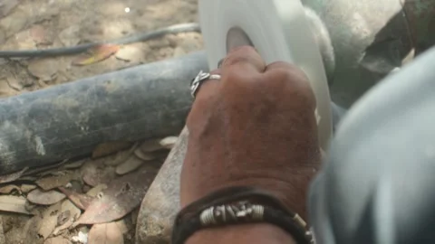 Over-the-shoulder close-up hands of a craftsman shaping a seashell using an Stock Footage 337941780