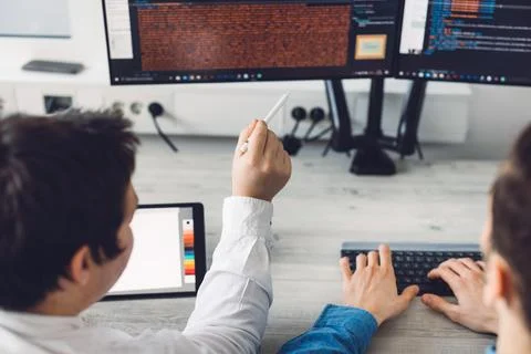 Over the shoulder close up view two programmers developing new app at work Stock Photos