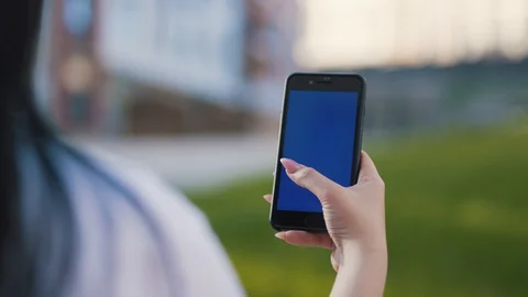 Over shoulder close up view of young woman holding smartphone with blank blue Stock Footage 111219331