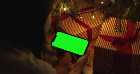 Over the shoulder hand holding iPhone 12 Pro Max with a horizontal green screen Stock Footage 146291928