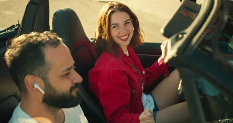 Over the shoulder a happy brunette guy listens to music with his girlfriend in a Stock Footage 280574964