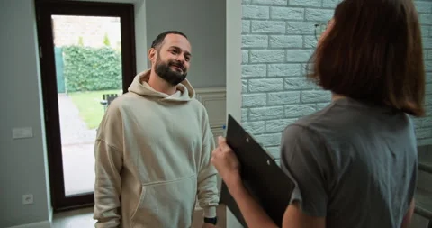 Over the shoulder a happy brunette guy with a beard comes to a realtor girl so Stock Footage 280637450