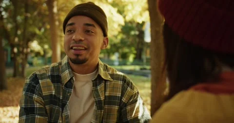 Over the shoulder a happy guy with black skin in a hat and a plaid shirt sits on Stock Footage 299924140