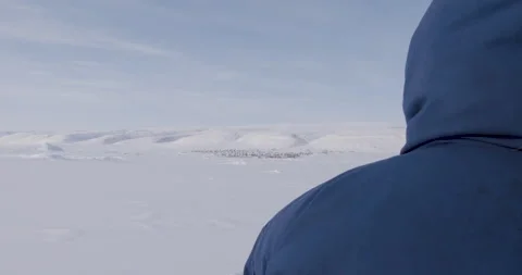 Over the shoulder of hunter on sled, town is seen in distance Stock Footage 138237315