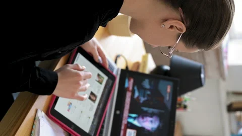 Over shoulder laptop screen view. Vertical videoWoman holding tablet and looking Video stock 153608899