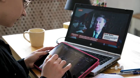 Over shoulder laptop screen view. Woman holding tablet and looking for Video stock 153609977