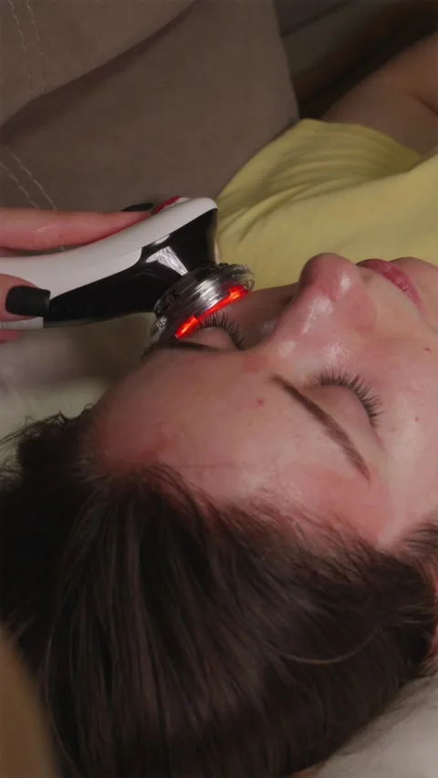 Over the shoulder shot of fixing face cream with minimalist red light device Vídeo Stock 344877049