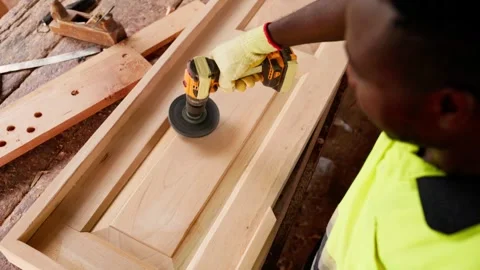 Over-the-shoulder shot of local African male carpenter refining a wooden door  Stock Footage 346733869