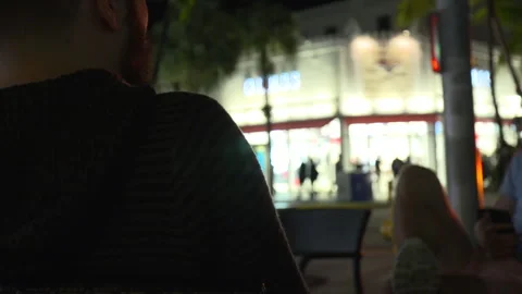 Over the shoulder shot of a man chatting outdoors at night Stock Footage 341857928